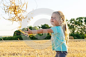 Little girl playing with wheat grass in the field