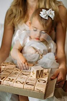 Little girl playing with wooden ABC blocks. Plastic-free wooden zero waste kids toys for safe and sustainable gifting. Eco