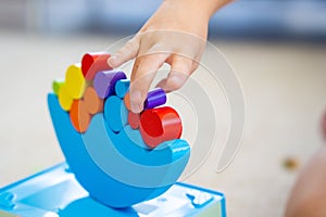 Little girl playing with wooden balancing toy on the floor in home living room. Focus on balancer