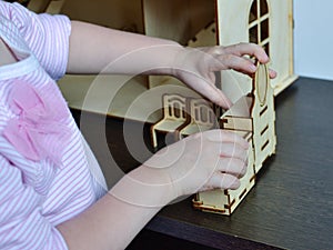 Little girl playing with wooden doll furniture