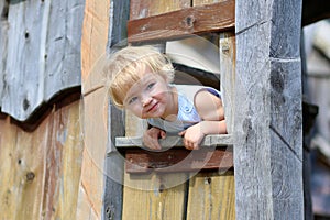 Little girl playing in wooden house in the park