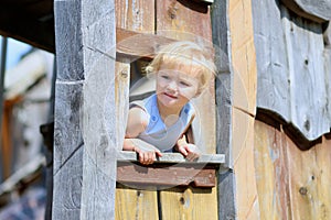 Little girl playing in wooden house in the park