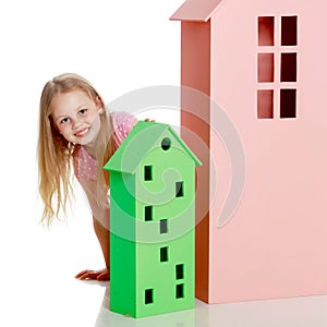 Little girl is playing with wooden houses.