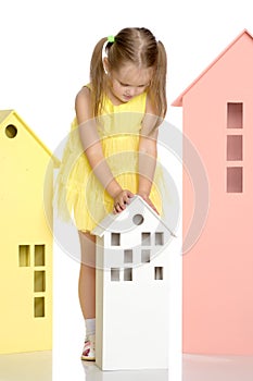 Little girl is playing with wooden houses.