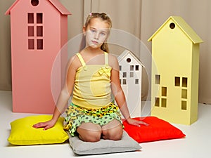 Little girl is playing with wooden houses.