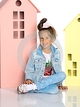 Little girl is playing with wooden houses.