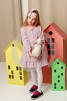 Little girl is playing with wooden houses.