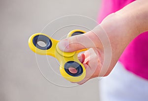Little girl is playing a yellow spinner