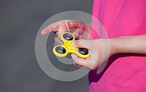 Little girl is playing a yellow spinner in her hand