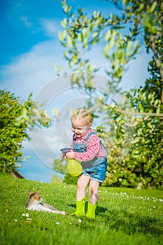 Little girl plays with a cat on a green grass