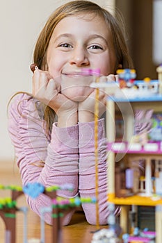 Little girl plays with a children`s constructor at home. Little girl playing with lots of colorful plastic blocks