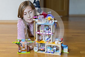 Little girl plays with a children`s constructor at home. Little girl playing with lots of colorful plastic blocks constructor and