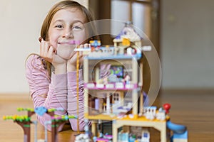 Little girl plays with a children`s constructor at home. Little girl playing with lots of colorful plastic blocks constructor and