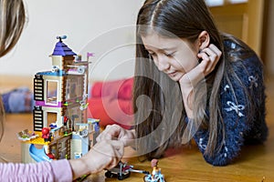 Little girl plays with a children`s constructor at home. Little girl playing with lots of colorful plastic blocks constructor and