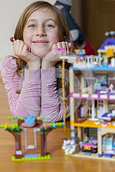 Little girl plays with a children`s constructor at home. Little girl playing with lots of colorful plastic blocks constructor and