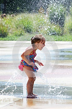 Little girl plays in city fountain