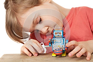 Little girl plays with clockwork robot isolated photo