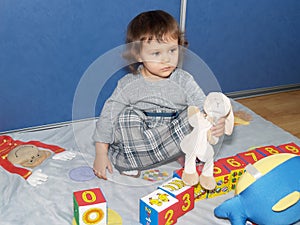 The little girl plays with cubes, sitting on a floor