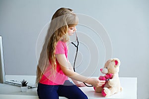 Little girl plays in doctor toy bear and stethoscope