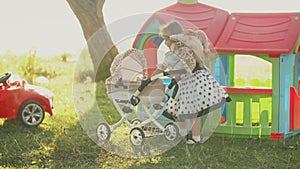 Little girl plays with a doll near a toy carriage