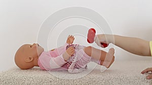 A little girl plays with a doll, and with a small neurological hammer, hits the knee of the doll. Child neurology