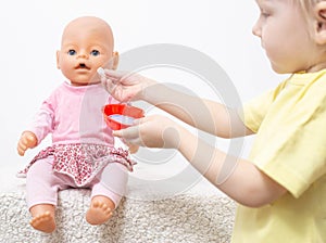 A little girl plays with a doll and treats her with pills. Pediatric medicine concept and treatment with pharmaceuticals