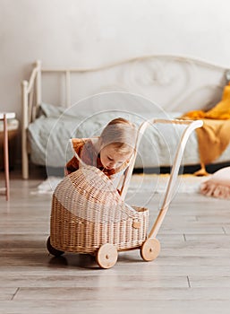 A little girl plays with dolls and a pram. The children`s room. Happy childhood