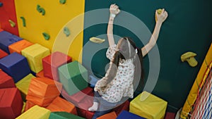 Little girl plays in an entertainment trampoline center. child rolls cubes of foam rubber.