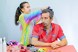 Little girl plays with her father at home in a beauty salon, combing her hair
