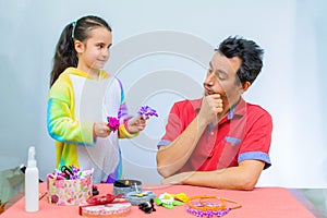 Little girl plays with her father at home in a beauty salon, combing her hair