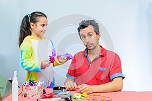 Little girl plays with her father at home in a beauty salon, combing her hair