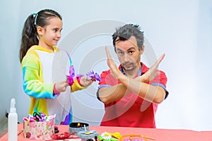 Little girl plays with her father at home in a beauty salon, combing her hair