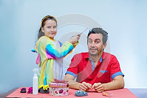 Little girl plays with her father at home in a beauty salon, combing her hair