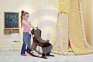 Little girl plays with hobbyhorse