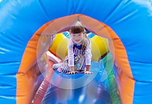 A little girl plays in an inflatable attraction at an amusement park on weekends. Cute baby on an inflatable trampoline. An Active