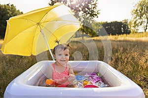 Little girl plays in the inflatable pool