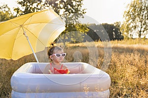 Little girl plays in the inflatable pool