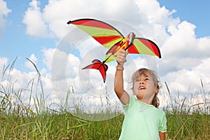 Little girl plays kite on meadow