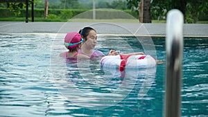 Little girl plays in the outdoor swimming pool of tropical resort during family summer vacation.