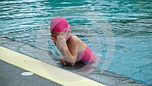 Little girl plays in the outdoor swimming pool of tropical resort during family summer vacation. Kids learning to swim.