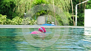 Little girl plays in the outdoor swimming pool of tropical resort during family summer vacation. Kids learning to swim.