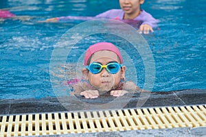 Little girl plays in the outdoor swimming pool of tropical resort during family summer vacation. Kids learning to swim. Healthy