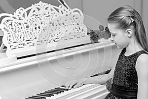 Little girl plays the piano, black and white photo.