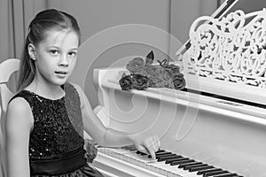 Little girl plays the piano, black and white photo.