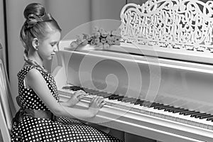 Little girl plays the piano, black and white photo.