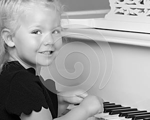 Little girl plays the piano, black and white photo.