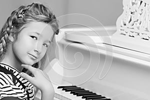 Little girl plays the piano, black and white photo.