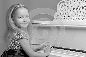 Little girl plays the piano, black and white photo.