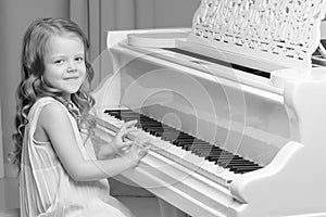 Little girl plays the piano, black and white photo.