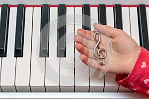 The little girl plays the piano. Hands of the musician on the piano keys while playing the instrument. Concert of Classical Music